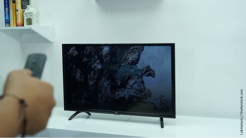 Tv piccola con mano che tiene un telecomando